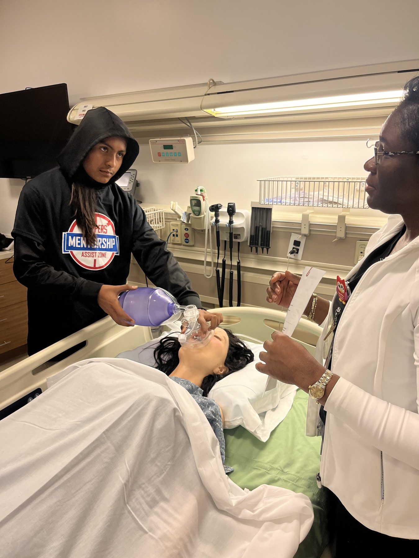 A teen practicing clinical skills in a hospital simulation lab