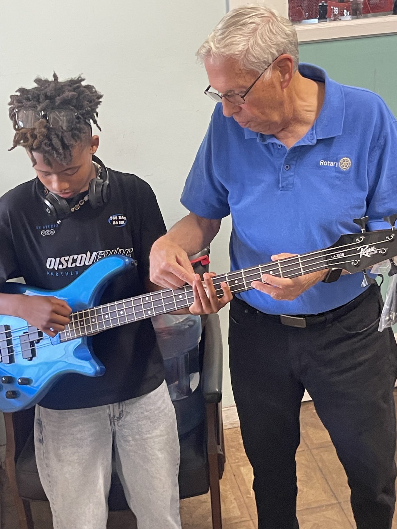 A Rotary volunteer teaching a pre-teen the bass