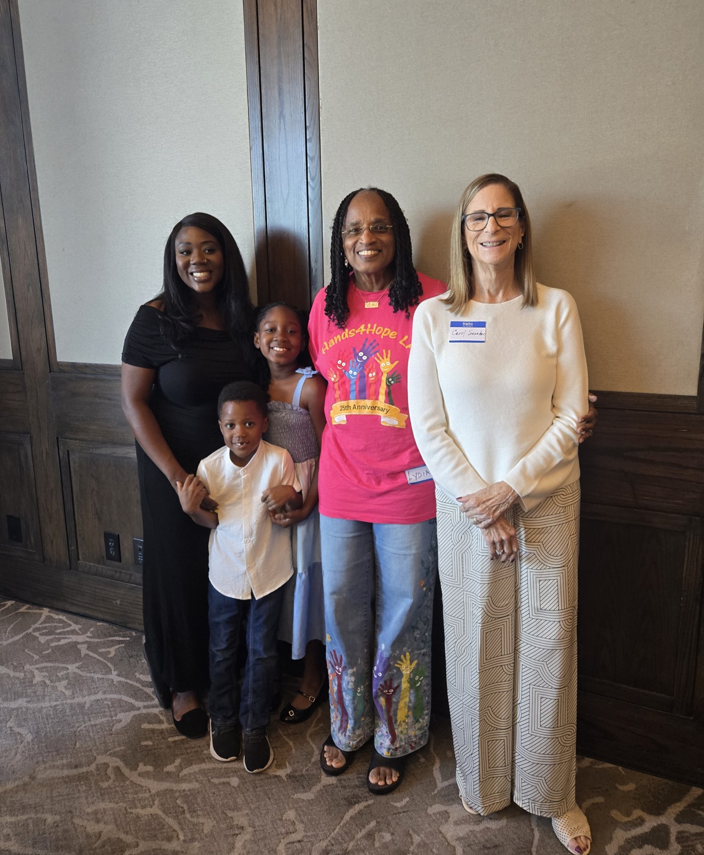 Sandy and her two kids with CEO Lydia Floyd and board member Carol Saunders